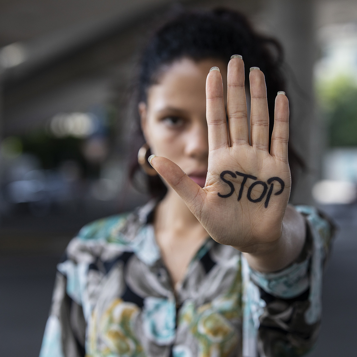 Une jeune femme lui tend la main avec le mot STOP écrit dessus.