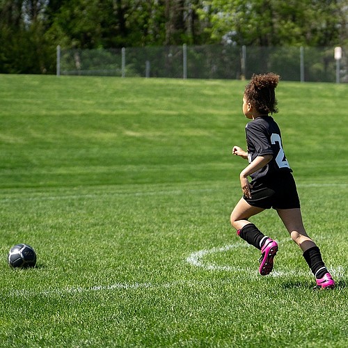 Un enfant qui court après un ballon sur un terrain de football