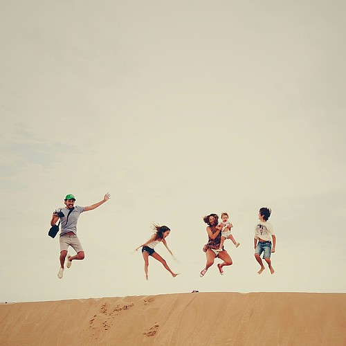 famille sautant en l'air sur une dune de sable